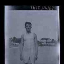 A young man in wet underwear on a riverbank