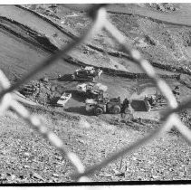 View through a fence of vehicles and equipment at Auburn Dam construction site