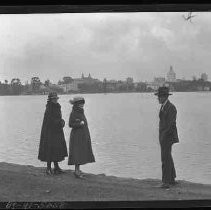 Three people standing along a shore