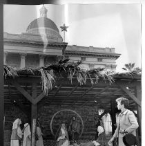 Exterior view of the north side of the California State Capitol showing the first Christmas nativity scene display created by a state employee on state property in 1959. Mrs. Lawrence Stutsman views the display