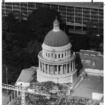 Aerial view of the California State Capitol building shrouded in skeletal-like scaffolding and steel supports. This view is the south end of the west wing