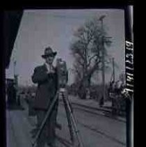 An unidentified men standing with a motion picture camera