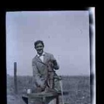 Young man pumping water from a hand pump