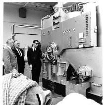 Three men looking at what appears to be an industrial washing machine