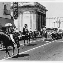 View of riders from the State Fair Rodeo leading a herd of longhorns up K Street during the State Fair Parade. This was the last fair held at the old fair grounds