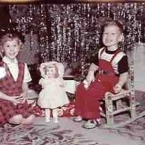 A boy and girl sitting under a Christmas tree