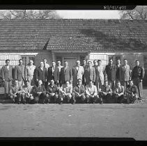 A group of men posed in front of a building