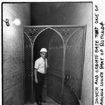 Dale Dwyer stands next to an ornate gate, one of two around the lower part of the California State Capitol rotunda