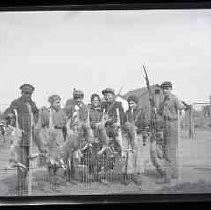 Four men and three women with rifles and dead rabbits