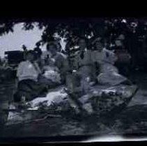 Four women and two babies sitting on a blanket with guns and dead doves