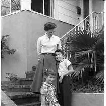 Woman, boy and a girl standing on steps of a house