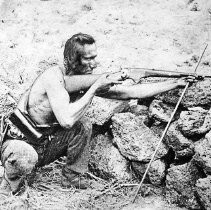 Native American Aims a Rifle from Behind a Rock Wall