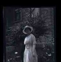 A woman posed in a light colored dress with hat