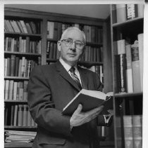 H. Harold Leavey, attorney and first chairman of the Sacramento Redevelopment Agency (1950); in his law library, holding a book