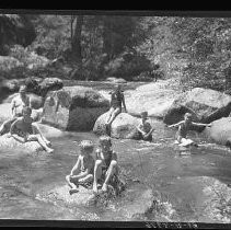 Children and adults playing and swimming in a river