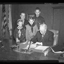 Boy Scouts with a man seated at a desk