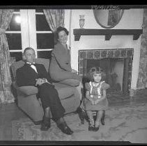 Unidentified family sitting next to a fireplace