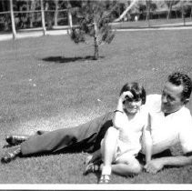 Man with girl in park sitting on the grass