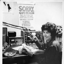 Rosemarie King, Berkeley newscaster, at the station consul, with a campaign sign for a city council election in the background