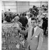 Sacramento Waste Disposal Company interior view of man standing next to bale of already-processed paper