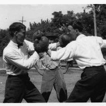 Two men boxing with third watching