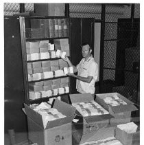 James D. Barnes, postal superintendent shown with stacks of envelopes awaiting stamps that commemorates the centennial of the Pony Express in 1960