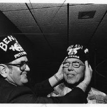 Ben Ali Shrine Potentate Ellis Katz places the 50-year fez on C. Alva Fisher (right)