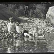 Three children at the edge of a river