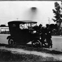 Two men standing front of automobile