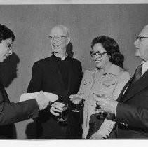 Father Dan Corona (left) pours champagne for Father Joseph King (second from left); also, Mrs. Cal O'Kane and Walter C. Kennedy Sr