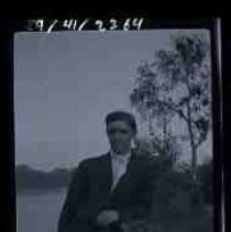 A photographic study of a young man leaning on a tree trunk