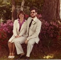 Color view of Mary A. Helmich and Walter P. Gray, III seated on an outside bench on their wedding day