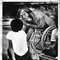 Gene Howard, a wheelchair athlete who competed in marathons, played tennis, and taught sports to handicapped children. He is shown listening to one of his students at Sac State