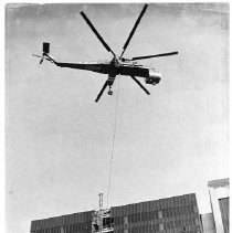 Helicopter lifting a crane section during construction of building at 555 Capitol Mall
