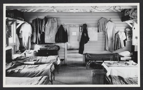 [view of interior of living quarters showing beds, clothes, and a game board]