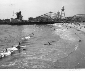 Surfers ride waves at a crowded beach