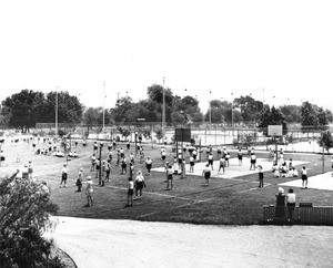 A group of women play the volleyball on a field near the base of the Hollywood Hills, not shown in this photograph