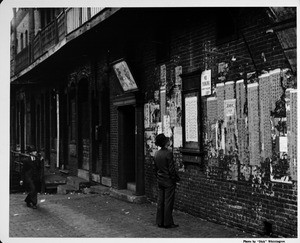 Men looking at wall of posters, posted bills in Chinatown