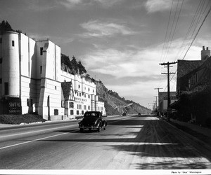 A car travels down a stretch road in Santa Monica with the Sorrento Beach Club on the left hand side