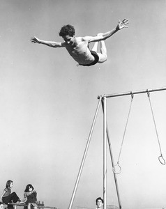 A gymnast practices his ring routine in the middle of a very busy Los Angeles playground