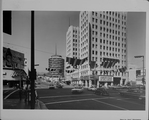 A street level shot of the corner at Hollywood Boulevard and Vine Street in Hollywood, showing American Airlines, Capitol Records, Hody's Restaurant, and E.F. Hutton, ca.1955-1965