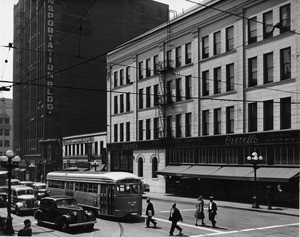 A modern looking streamlined trolley is stopped at the intersection of Seventh Street and Main Street in front of Overell's