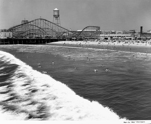 People swimming at a beach await the arrival of a large wave