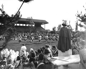 A dance troupe performs for a large crowd in the middle of Exposition Park