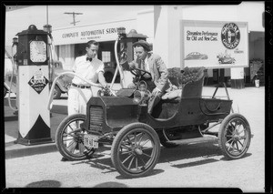 Old REO car with streamline poster on it, with colored boys & at station, Southern California, 1934