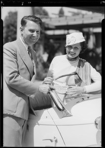 Lita Ray and Cliff Henderson putting Air Races stickers on car, Southern California, 1933