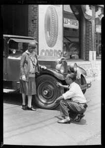 Tire changing on car of Mrs. Reed, Southern California, 1929