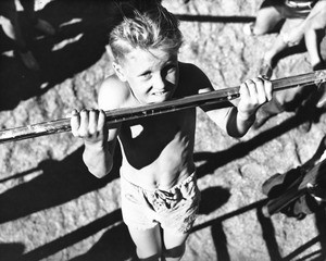 A young boy practices his chin-ups on one of many playground bars