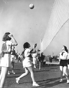 A group of women compete in a game of volleyball