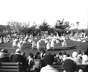 A dance troupe performs for a large crowd in the middle of Exposition Park